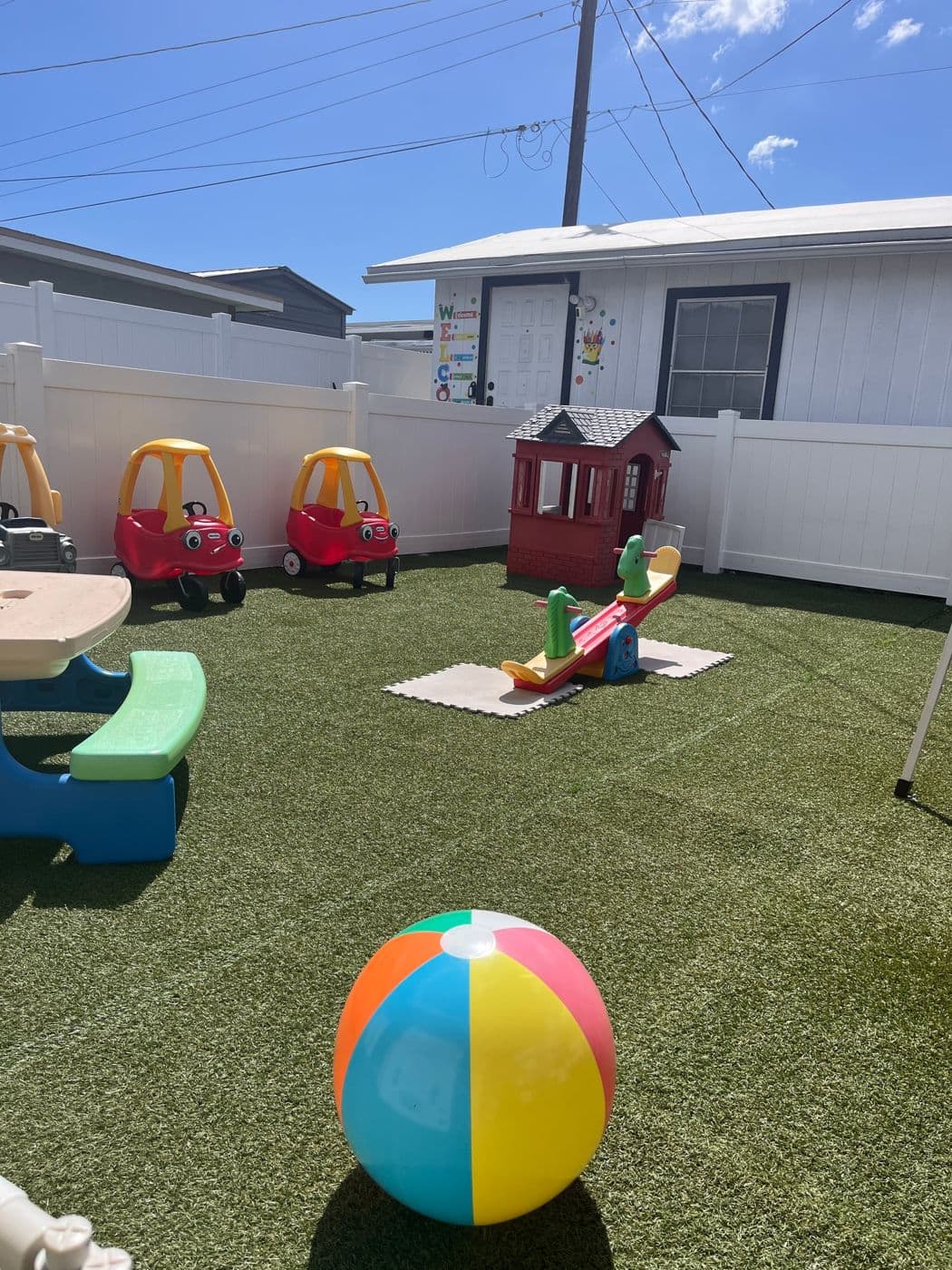 Patio cercado con carritos, una casita y una pelota de playa